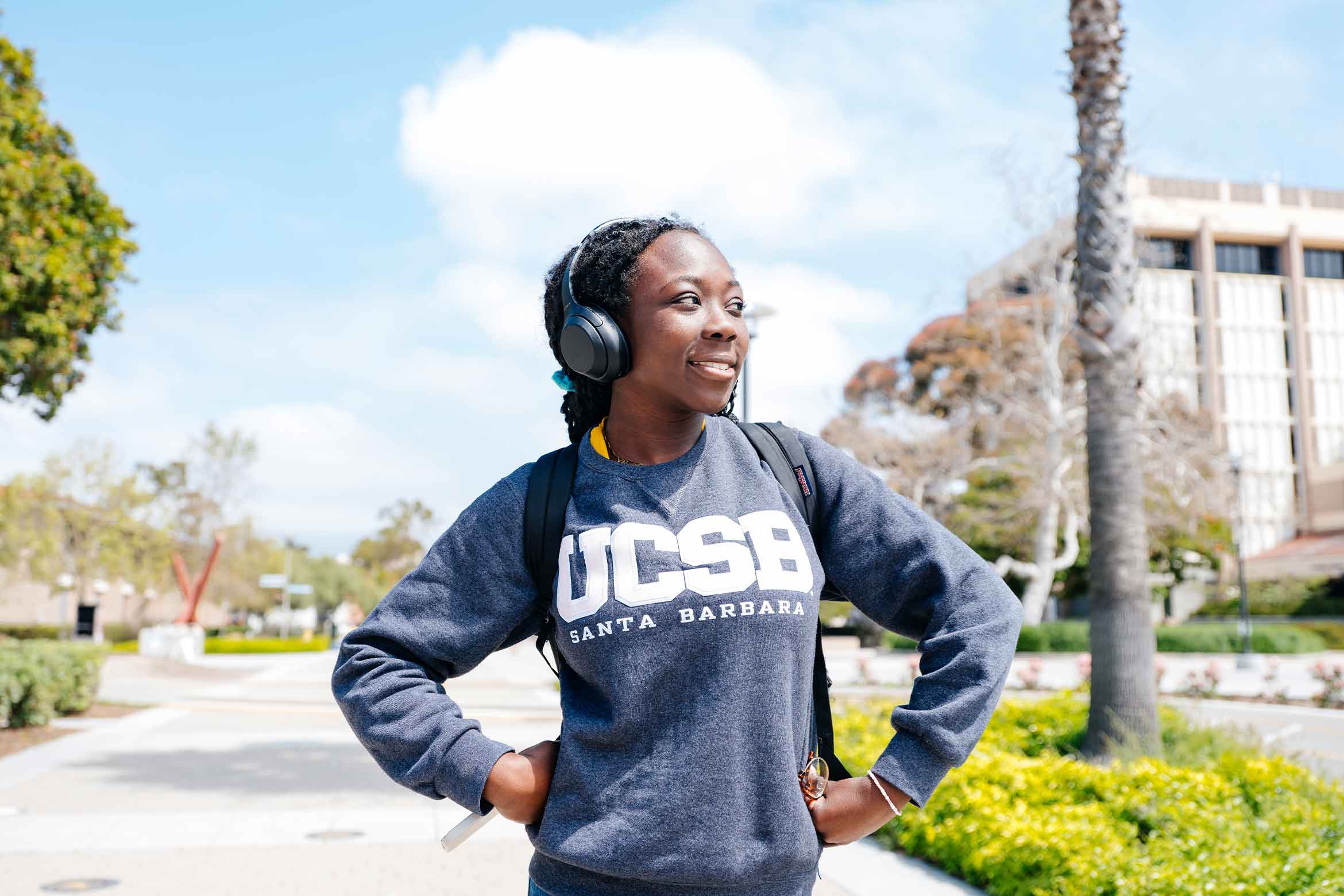 A student wearing headphones and a UCSB sweater looking off in the distance.