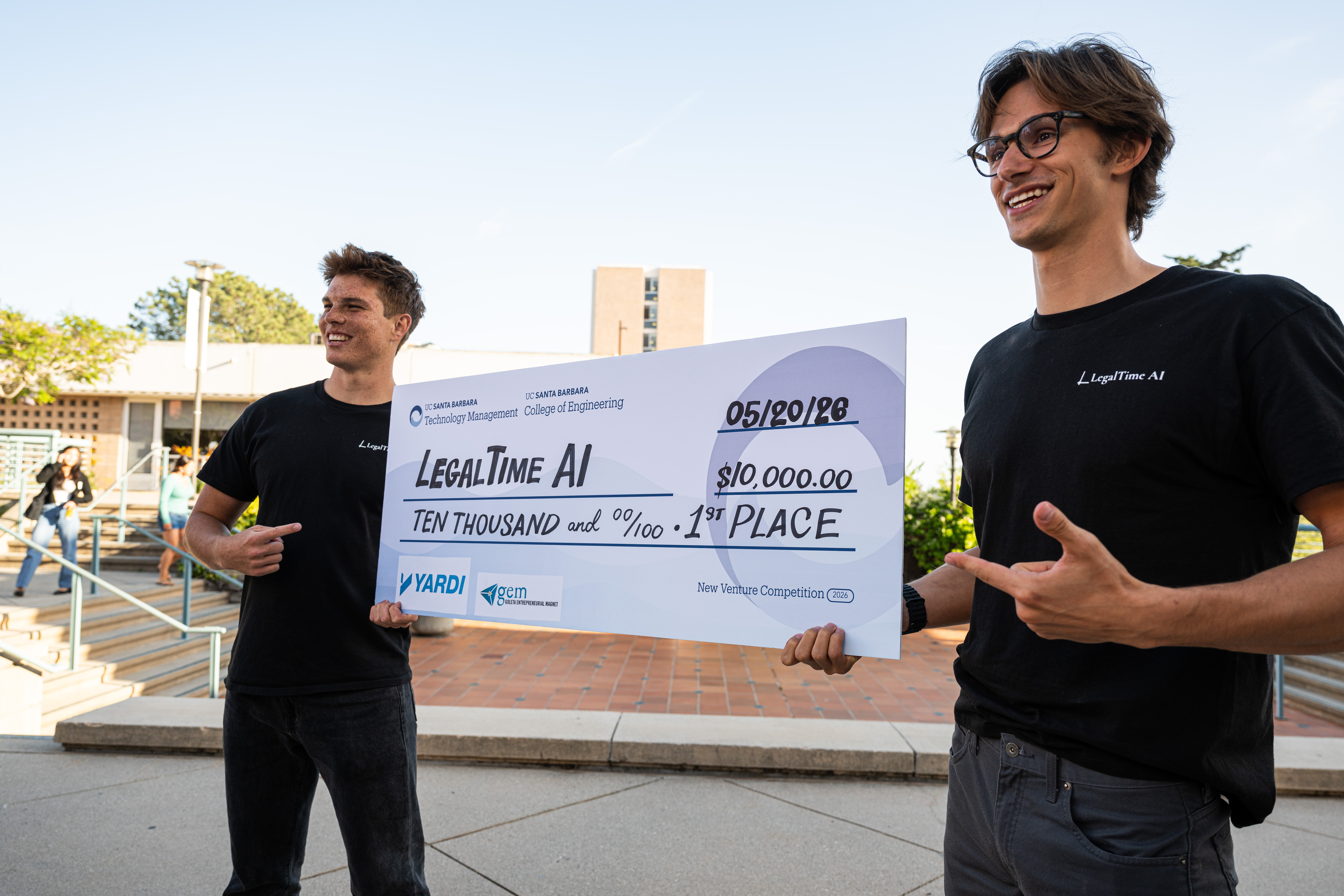 Two students hold up a prize money check