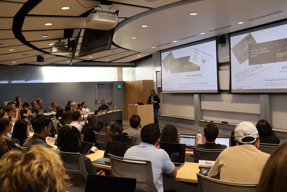 A large classroom filled with students with a woman lecturing at podium
