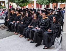 photo of the graduates sitting down in their cap and gowns