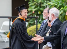 Max Hinson receives his graduate certificate and shakes the hands of MTM faculty