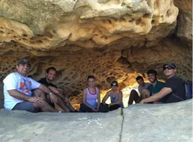 photo of the seven students sitting down in a cave