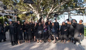 photo of the graduates lined up throwing their caps into the air