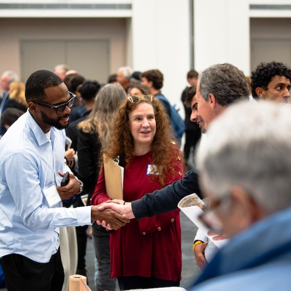 A photo of colleagues shaking hands in a crowded space