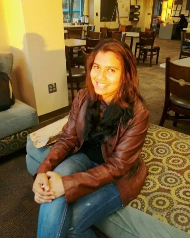 photo of harshitha posing in a residence sitting atop of a couch