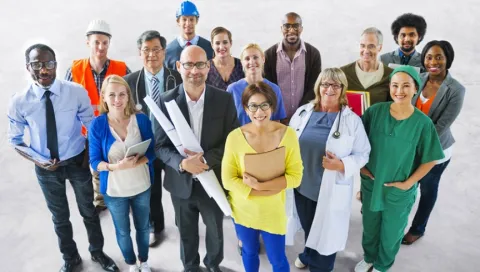 stock photo of a group of adults dressed in various different outfits from different professions look up at the camera