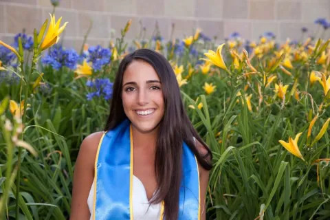 headshot of Anna Ashe wearing her 2016 sash standing in front of a field of yellow flowers