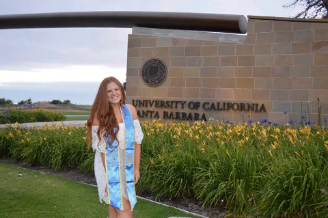 Madison poses with her 2017 sash in front of the UCSB sign