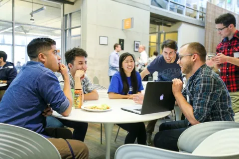 a group of students sit at a round table in conversation