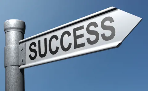 photo of a white street sign with the word "success"