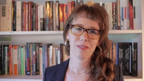 virginia leavell headshot. behind her are shome white shelves filled with books