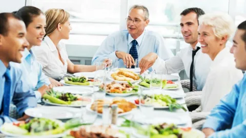 a group of businesspeople sitting around a table eating lunch