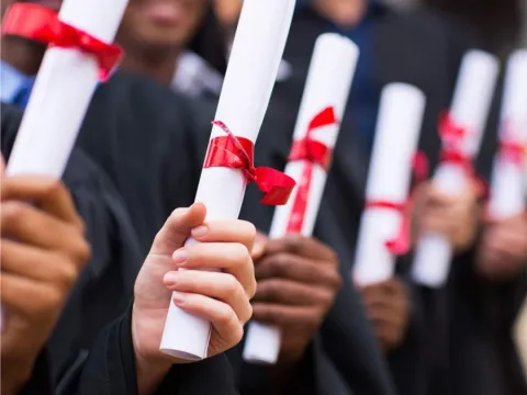 a group shot of student's hands holding out their diploma's