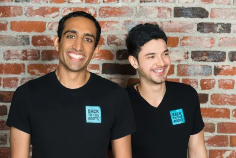 Nikhil Arora and Alejandro Velez smiling and wearing black t-shirts that read "back to the roots"