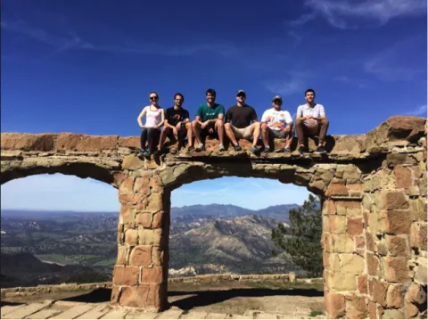 Steve Duneier and 5 other students sitting on a ledge of Knapp's Castle
