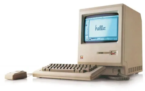 product photo of an old apple computer with a keyboard and mouse, the screen says "hello" in a curvy font