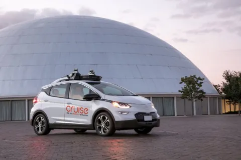 one of lidar's delf-driving cars in front of a big dome building. a sunset lights the background