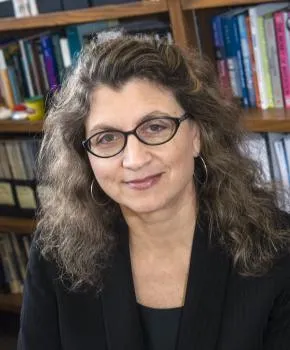 Mary Tripsas seated in front of bookshelf.